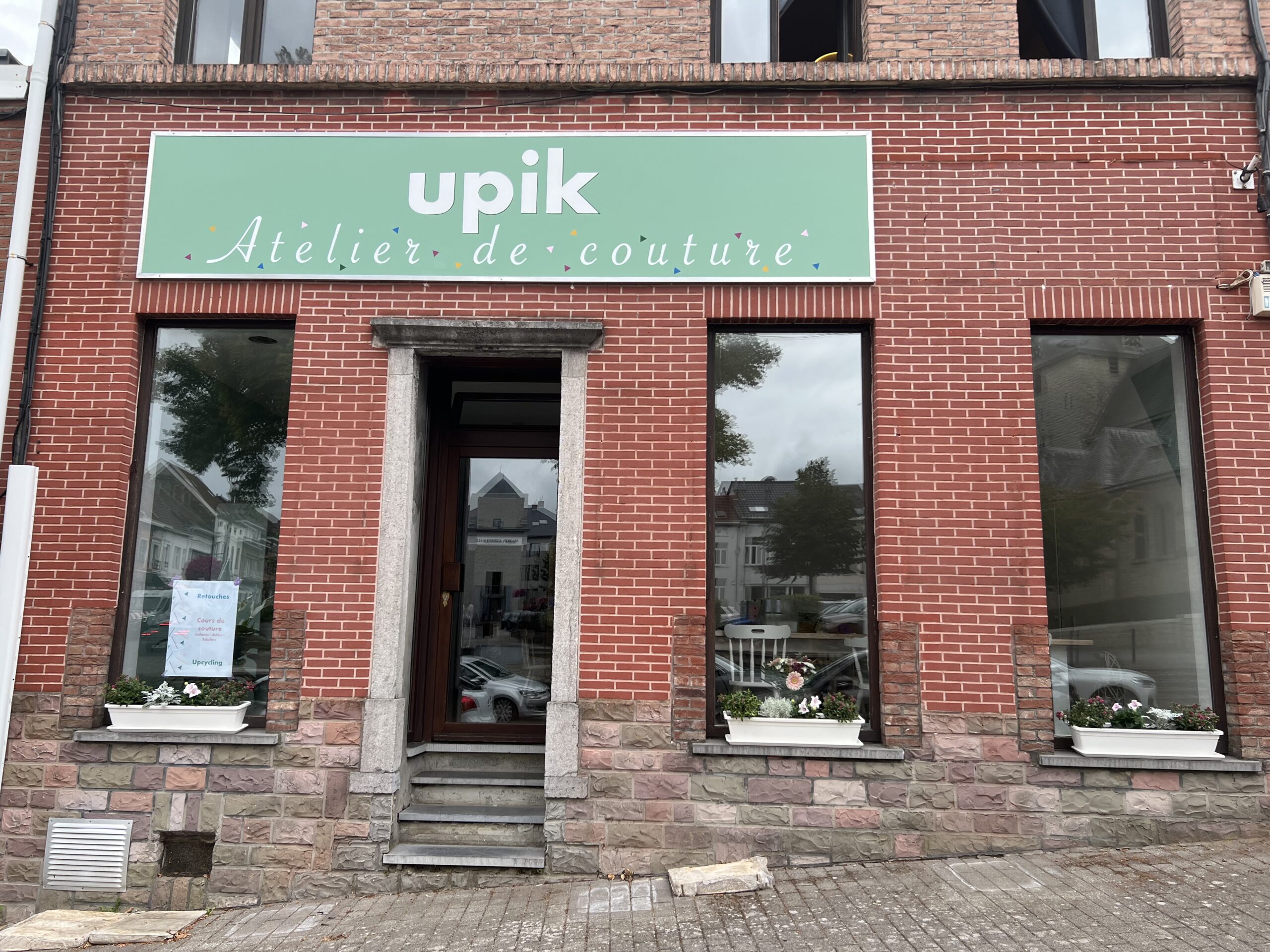 Facade et vitrine du magasin : l'Atelier de couture Upik qui propose de la retouche et réparation de couture et des cours de couture